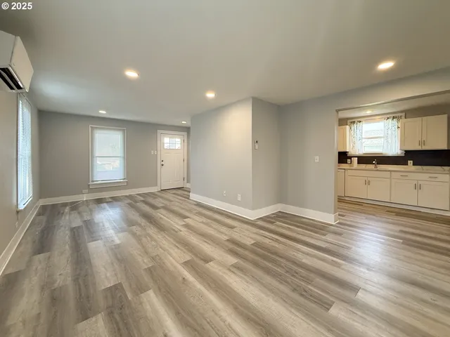 a view of empty room with kitchen and window