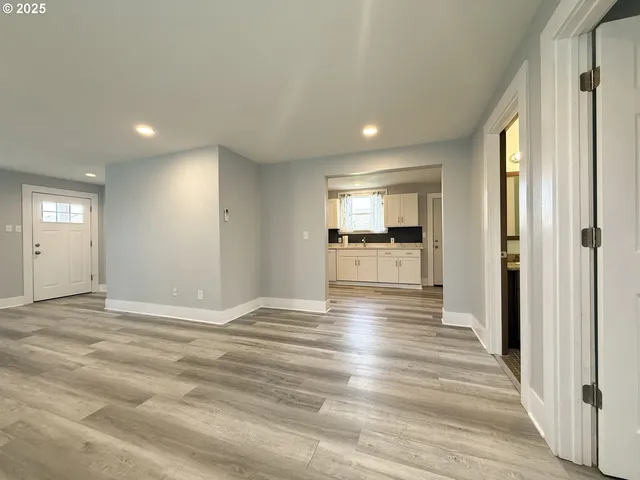 a view of a livingroom with wooden floor and a kitchen