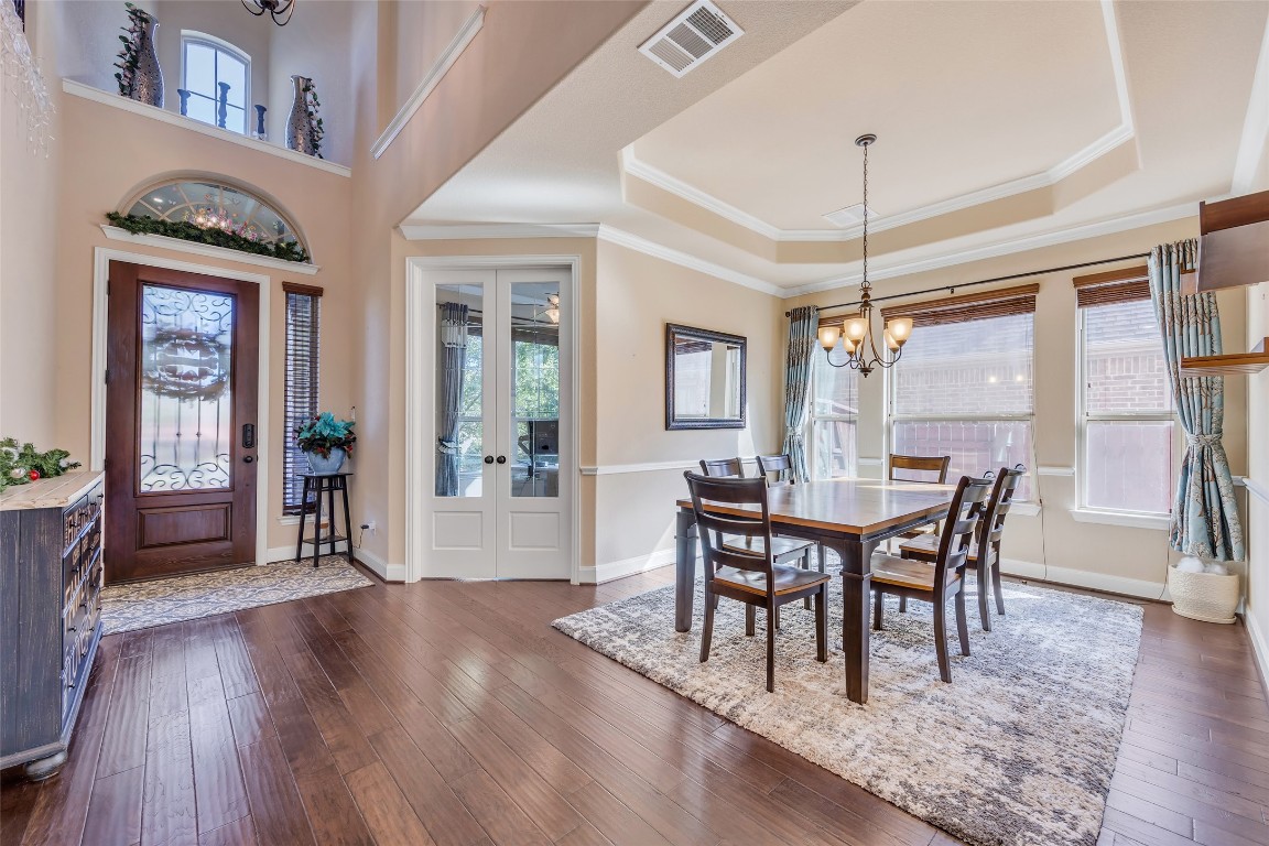 103 County Road 180, Unit 23 Leander, TX 78641 - Photo 4 of 40 a dining room with wooden floor a chandelier a wooden table and chairs