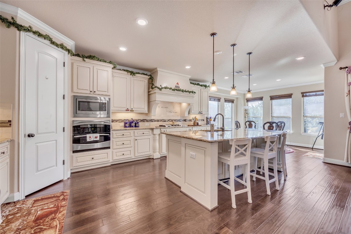 103 County Road 180, Unit 23 Leander, TX 78641 - Photo 8 of 40 a kitchen with stainless steel appliances kitchen island granite countertop a wooden floor and white cabinets