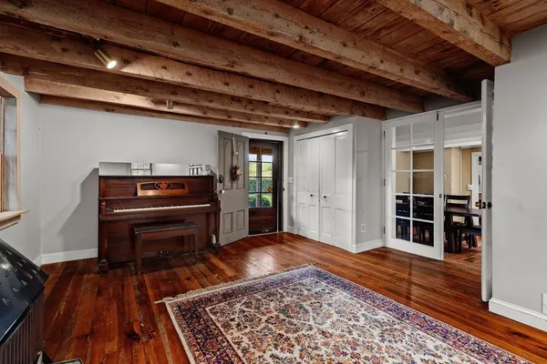 a view of a livingroom with wooden floor a piano and windows