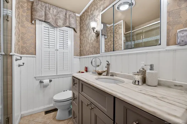 a bathroom with a granite countertop sink a toilet and a mirror