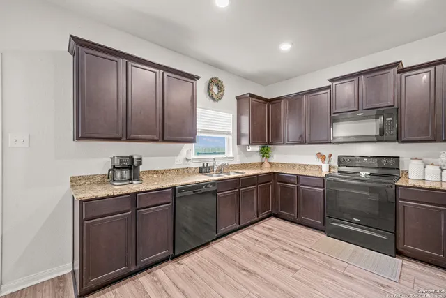 a kitchen with stainless steel appliances granite countertop wooden cabinets a stove top oven with a sink and dishwasher