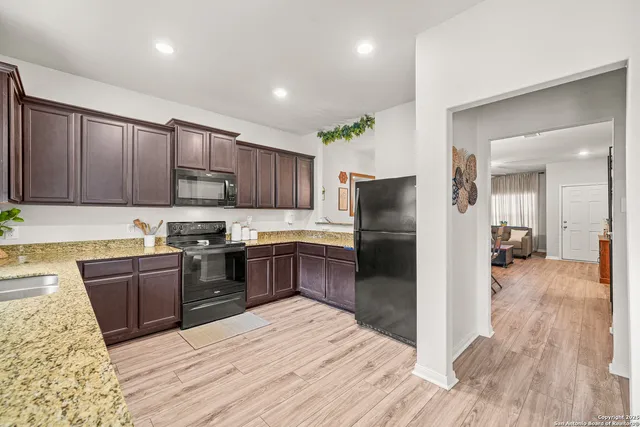 a kitchen with stainless steel appliances granite countertop a refrigerator a sink dishwasher a stove with wooden cabinets and floor