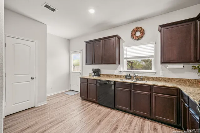 a kitchen with stainless steel appliances granite countertop wooden cabinets a stove a sink and dishwasher with wooden floor