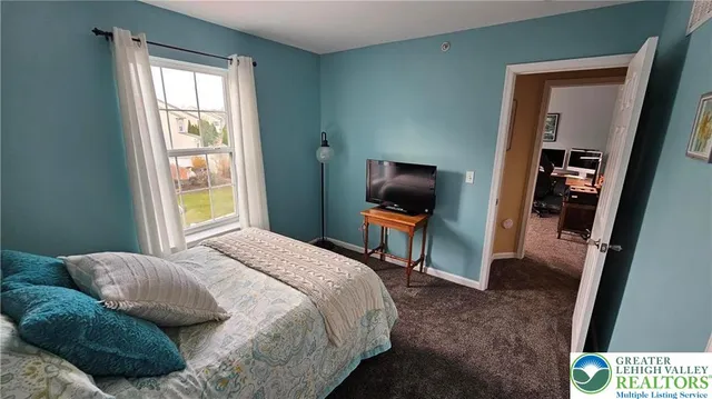 a bedroom with a bed and a flat tv screen on dresser