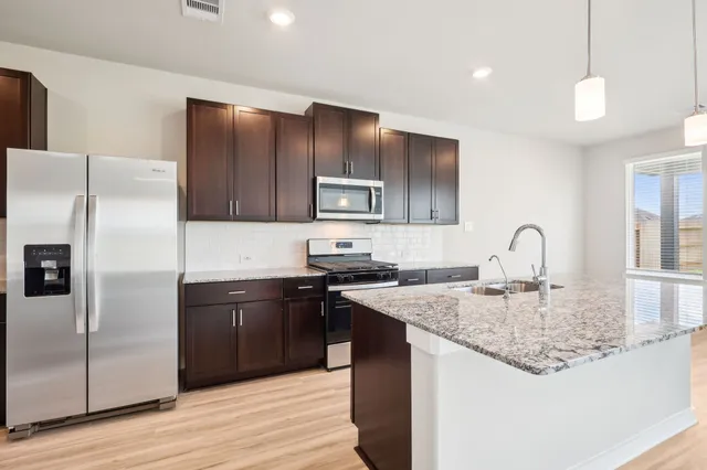 a kitchen with stainless steel appliances granite countertop a sink stove and refrigerator