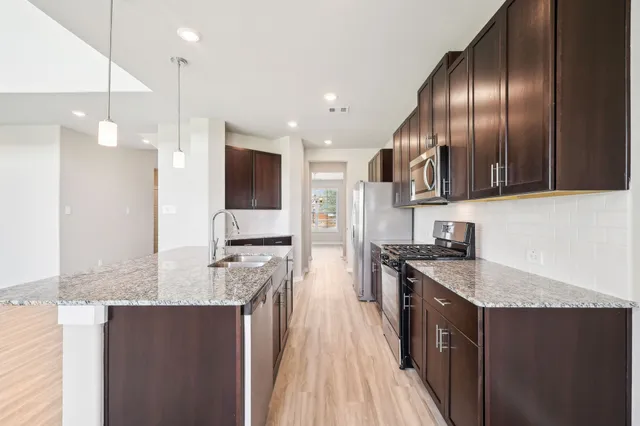 a kitchen with granite countertop stainless steel appliances a sink stove and refrigerator
