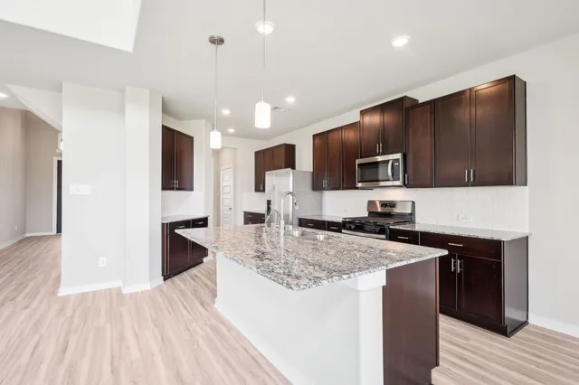 a kitchen with granite countertop a sink a counter top space appliances and cabinets