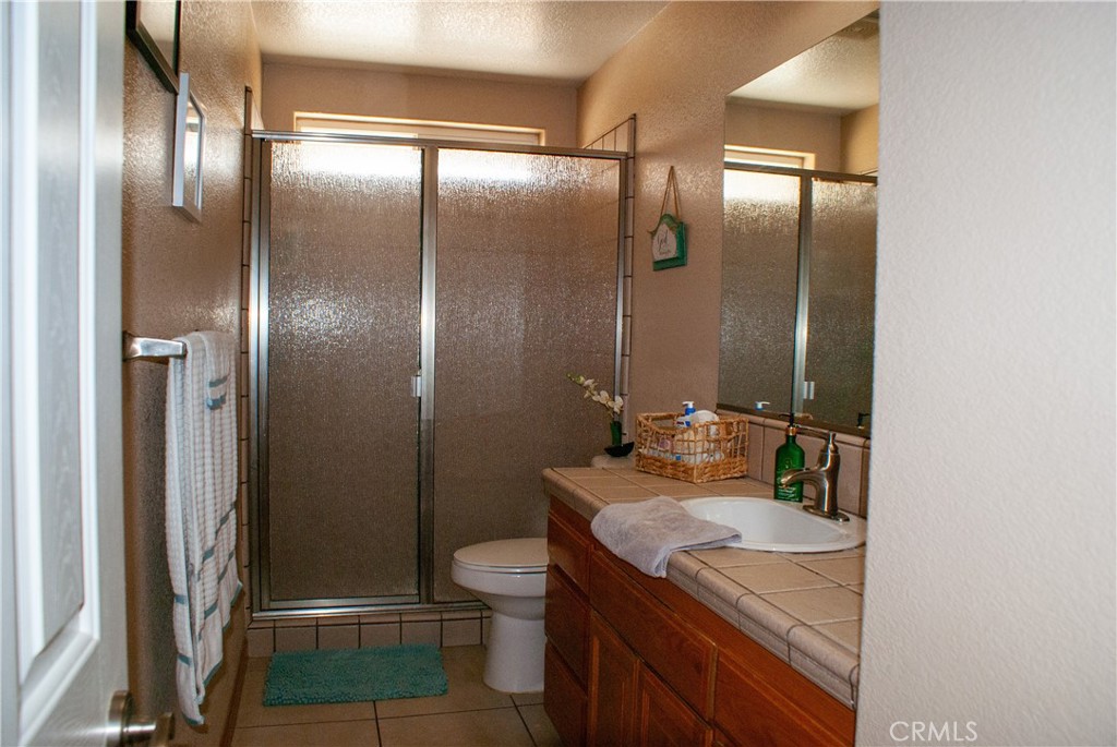 8465 Cedar Court Phelan, CA 92371 - Photo 19 of 51 a bathroom with a granite countertop sink a toilet a mirror and shower