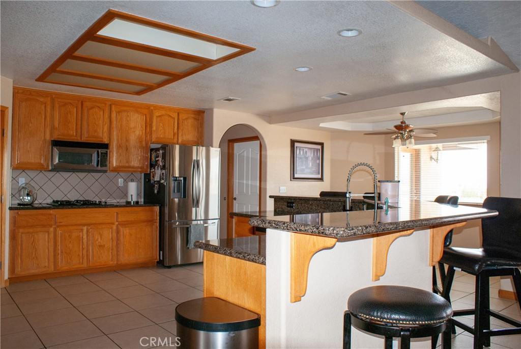 8465 Cedar Court Phelan, CA 92371 - Photo 31 of 51 a kitchen with stainless steel appliances granite countertop a stove top oven a sink a dining table and chairs