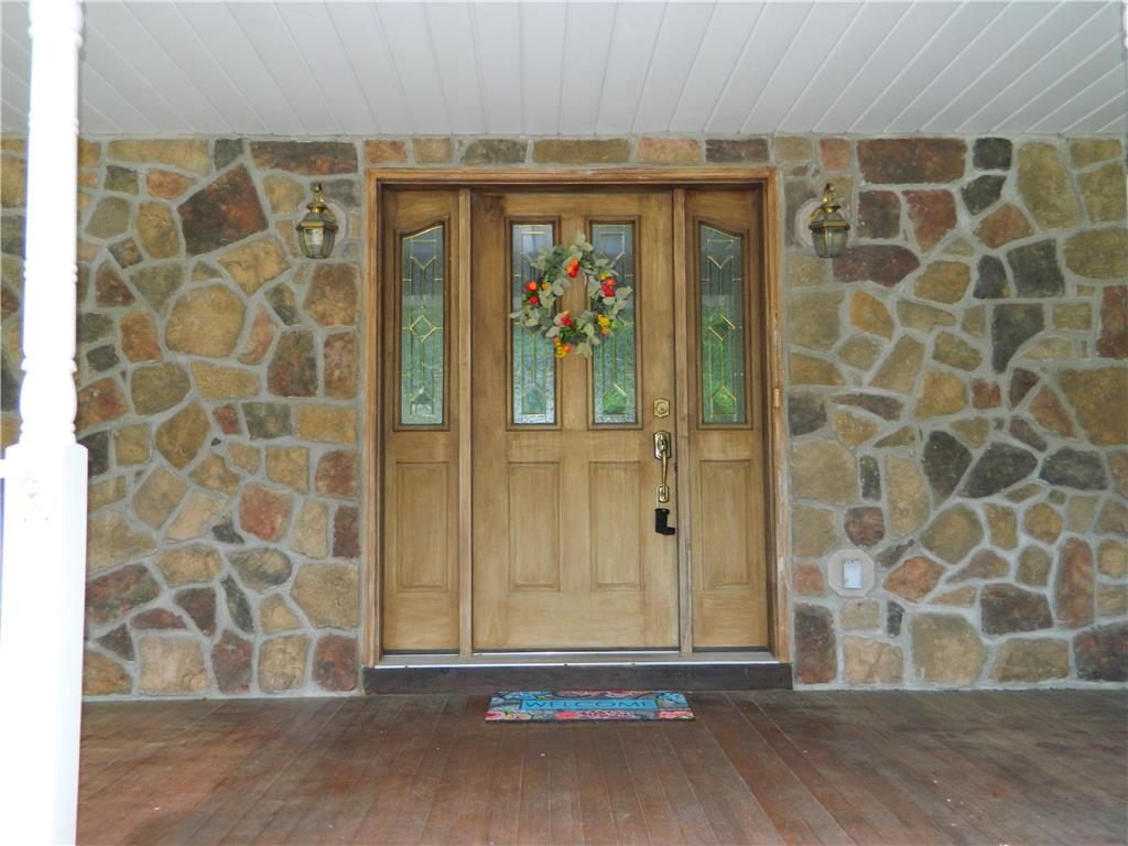 328 Pin Oak Road Stroudsburg, PA 18360 - Photo 6 of 42 A welcoming wooden entry door with leaded glass sidelights is set against a handsome stone facade.