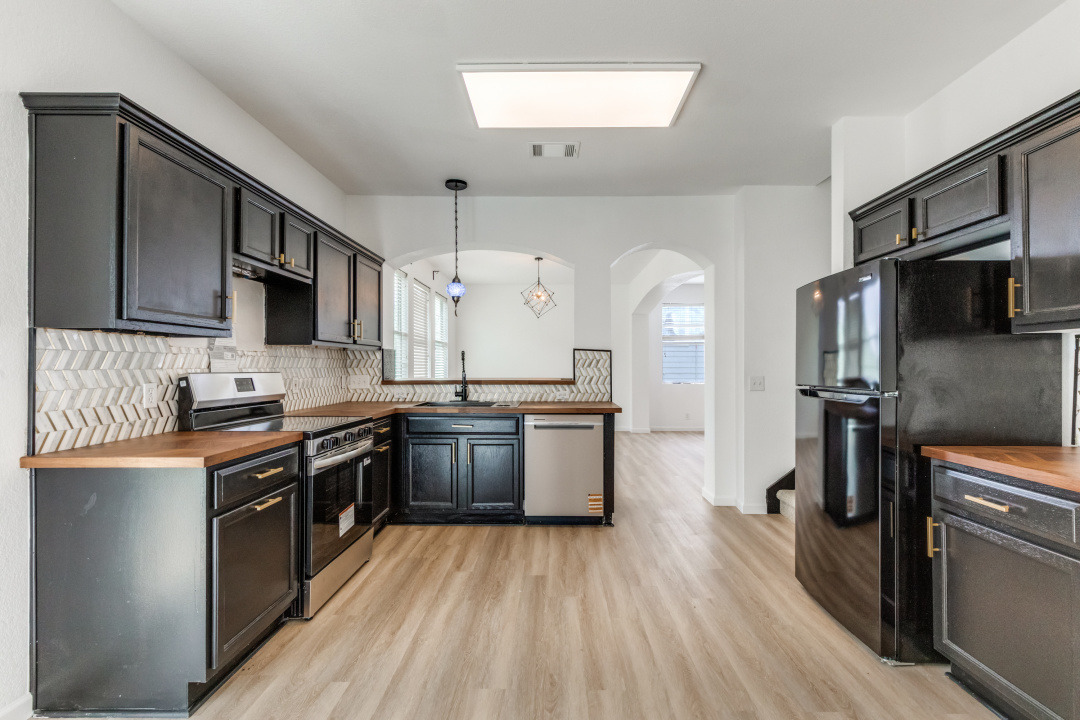 9204 Magna Carta Loop Austin, TX 78754 - Photo 11 of 27 Kitchen with wood counters, stainless steel appliances, light wood-style floors, decorative light fixtures, and healthy amount of natural light