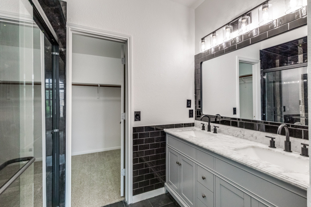 9204 Magna Carta Loop Austin, TX 78754 - Photo 19 of 27 Full bath with a spacious closet, double vanity, a stall shower, tile walls, and wainscoting