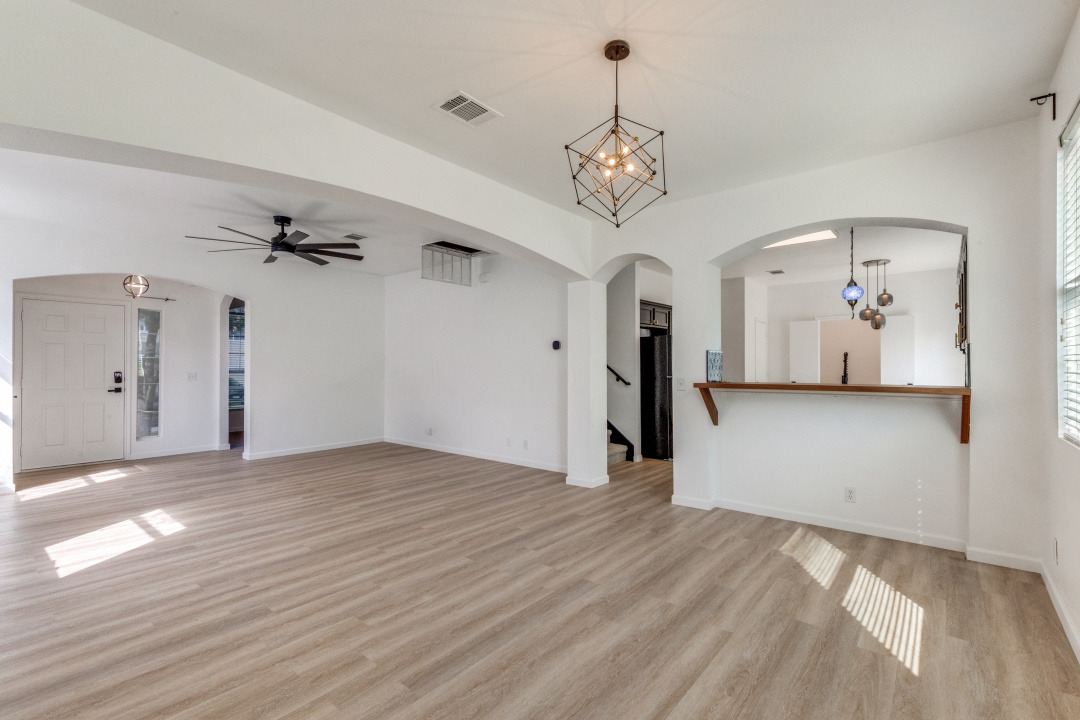 9204 Magna Carta Loop Austin, TX 78754 - Photo 7 of 27 Unfurnished living room with arched walkways, a chandelier, light wood-type flooring, and a ceiling fan