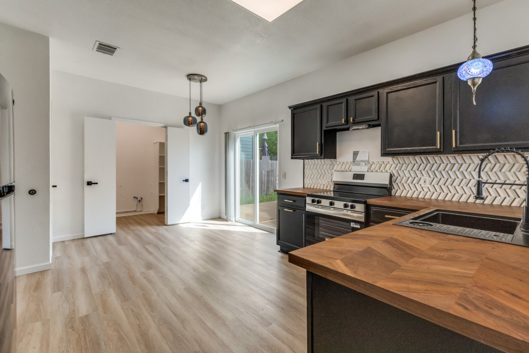 9204 Magna Carta Loop Austin, TX 78754 - Photo 9 of 27 Kitchen with butcher block countertops, stainless steel range with electric stovetop, decorative light fixtures, and light wood finished floors