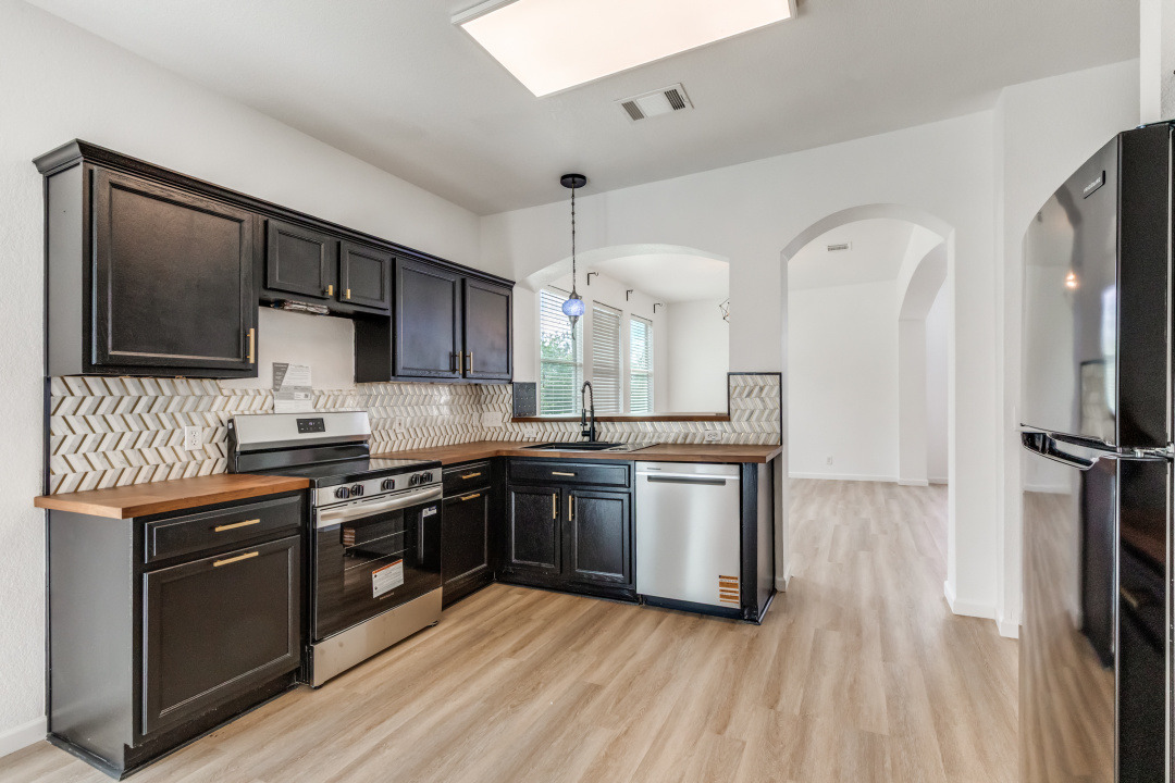9204 Magna Carta Loop Austin, TX 78754 - Photo 10 of 27 Kitchen featuring tasteful backsplash, butcher block counters, stainless steel appliances, light wood-type flooring, and arched walkways