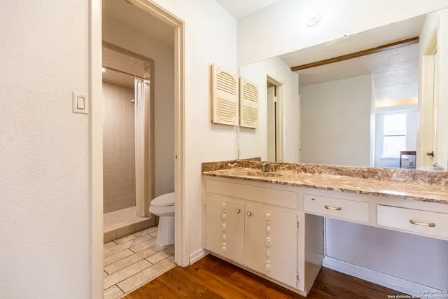 a bathroom with a granite countertop toilet a sink and a mirror