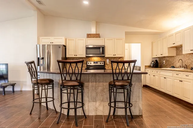 a kitchen with stainless steel appliances a dining table chairs and granite counter tops