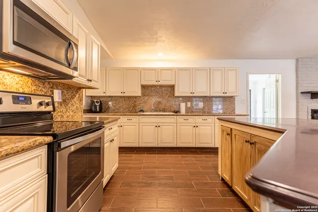 a kitchen with stainless steel appliances granite countertop a stove a sink and a refrigerator