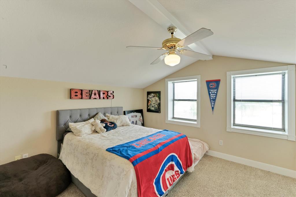 2717 Clear Lake Road Weatherford, TX 76087 - Photo 34 of 40 Carpeted room featuring a sloped ceiling with exposed beam, two windows, and a ceiling fan with integrated lighting