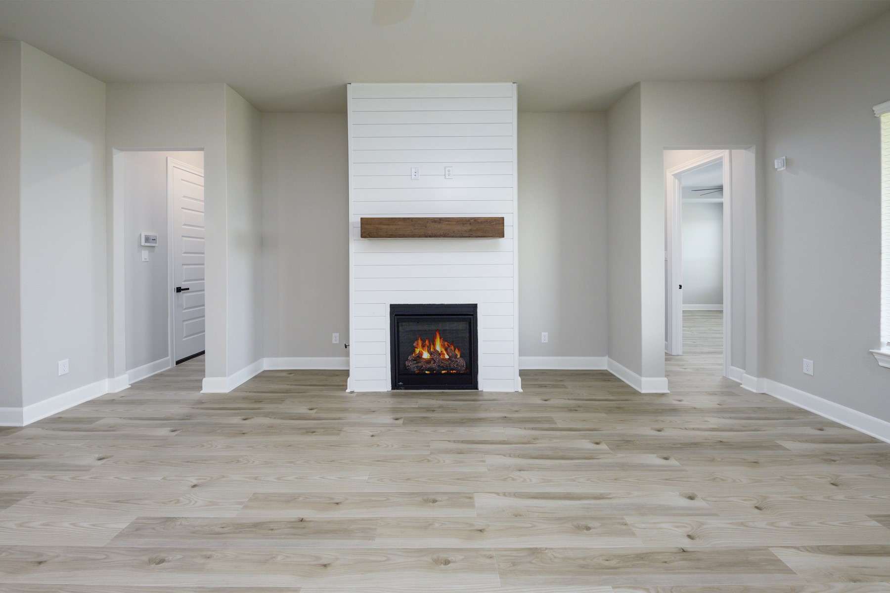 1926 June Lk Lane Iowa Colony, TX 77583 - Photo 2 of 15 Step into the heart of the home—this inviting living room features a cozy fireplace with shiplap surround and rustic wood mantle, perfectly framed by neutral tones and wide-plank luxury vinyl flooring. Open to the kitchen, it's an ideal space for entertaining or relaxing, with seamless flow and natural light.