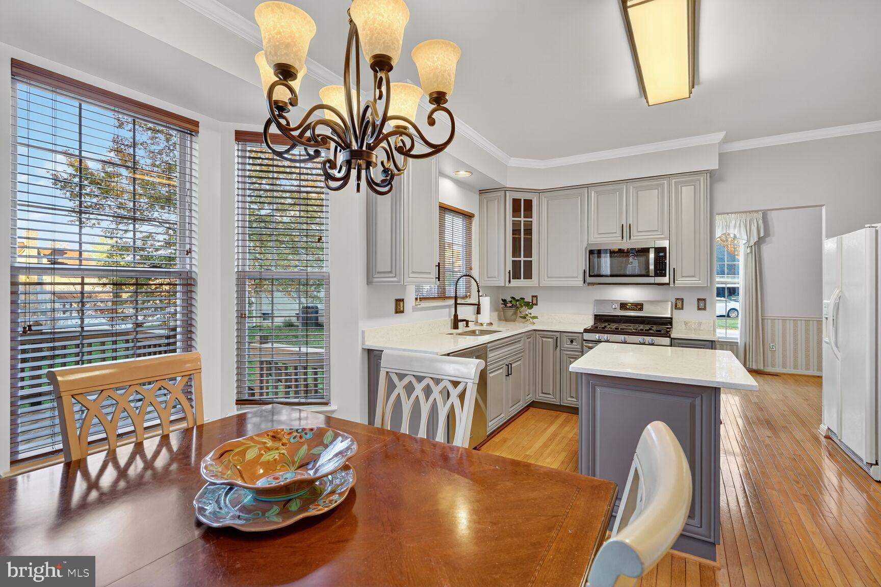 8205 Swamp Rose Place Laurel, MD 20724 - Photo 8 of 34 a kitchen with stainless steel appliances kitchen island granite countertop a stove a refrigerator a sink a dining table and chairs with wooden floor