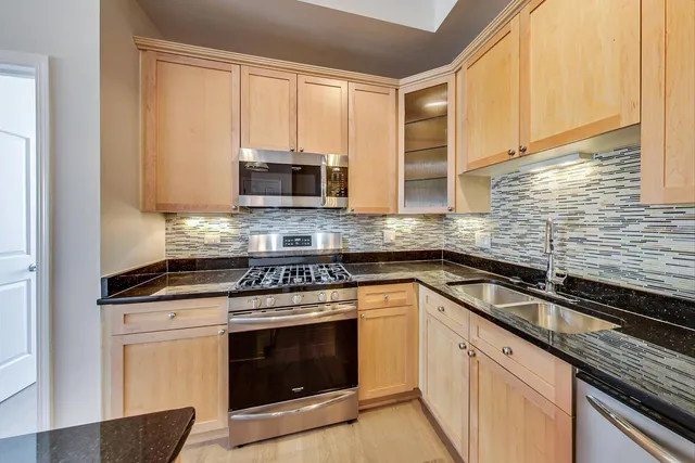 a kitchen with granite countertop a stove top oven cabinetry a sink and a window