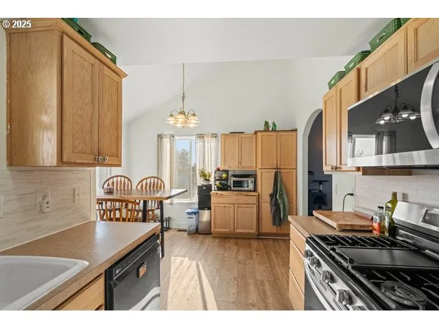 a kitchen with a refrigerator a stove a sink dishwasher and wooden cabinets with wooden floor