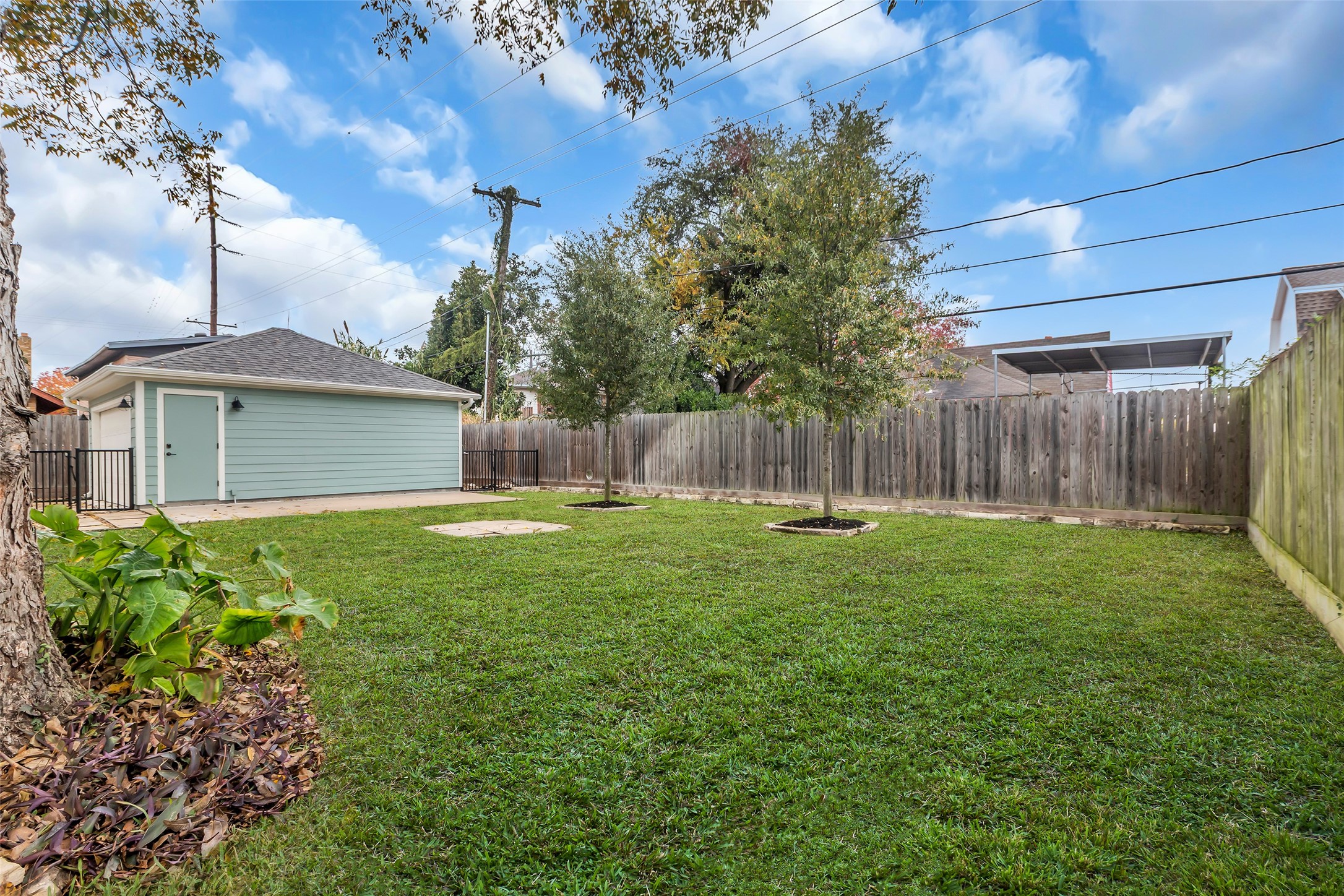 2611 Ruth Street Houston, TX 77004 - Photo 47 of 50 The backyard is enclosed by a tall wooden fence and features a grassy area, providing privacy and space for outdoor activities.