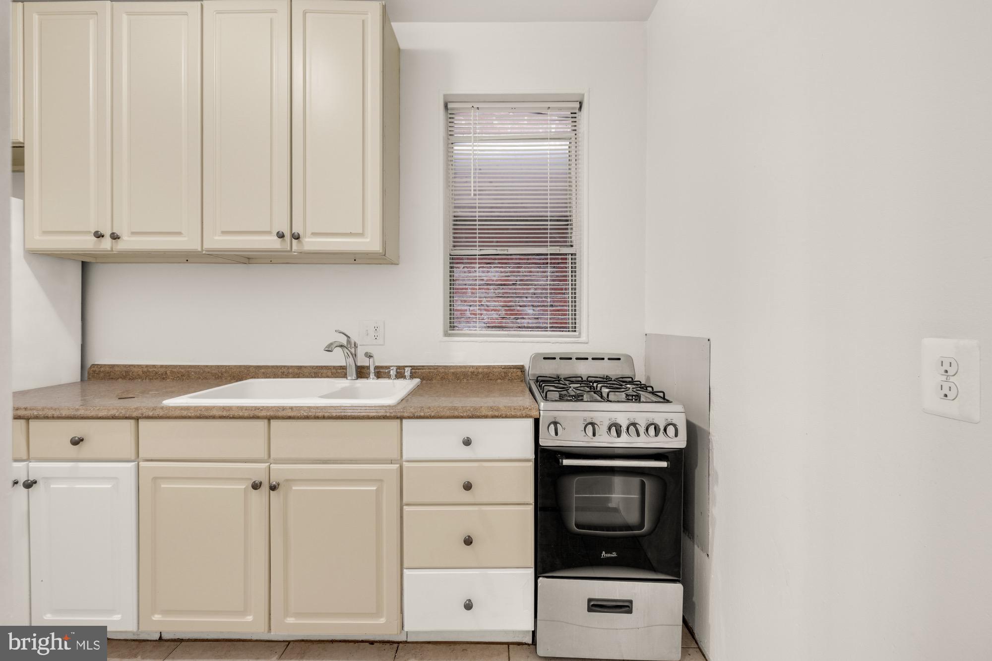1102 K Street Southeast Washington, DC 20003 - Photo 6 of 30 a kitchen with granite countertop a stove a oven and white cabinets