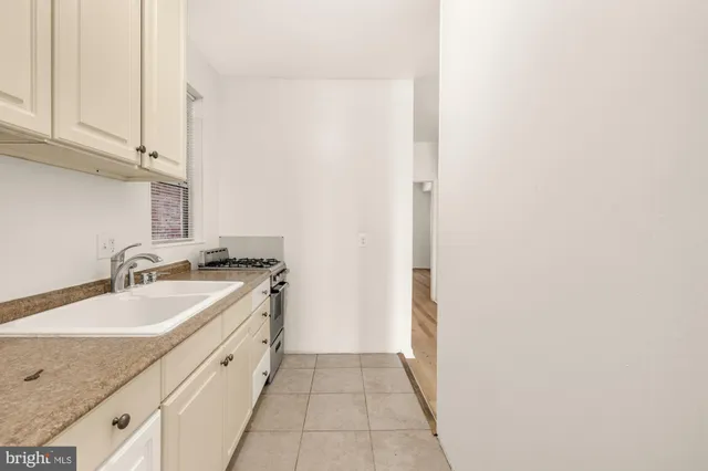 a kitchen with granite countertop a stove a sink and white cabinets with wooden floor
