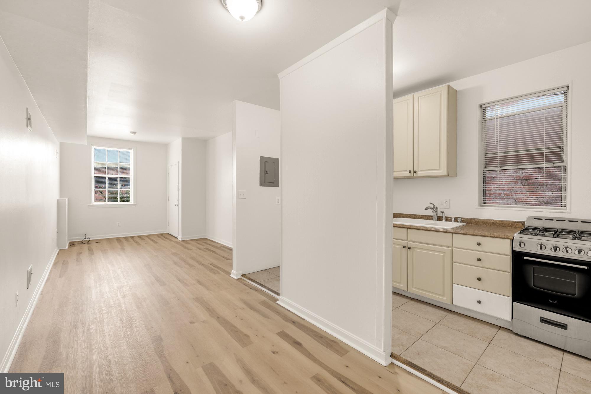 1102 K Street Southeast Washington, DC 20003 - Photo 9 of 30 a kitchen with granite countertop a stove a sink and white cabinets with wooden floor