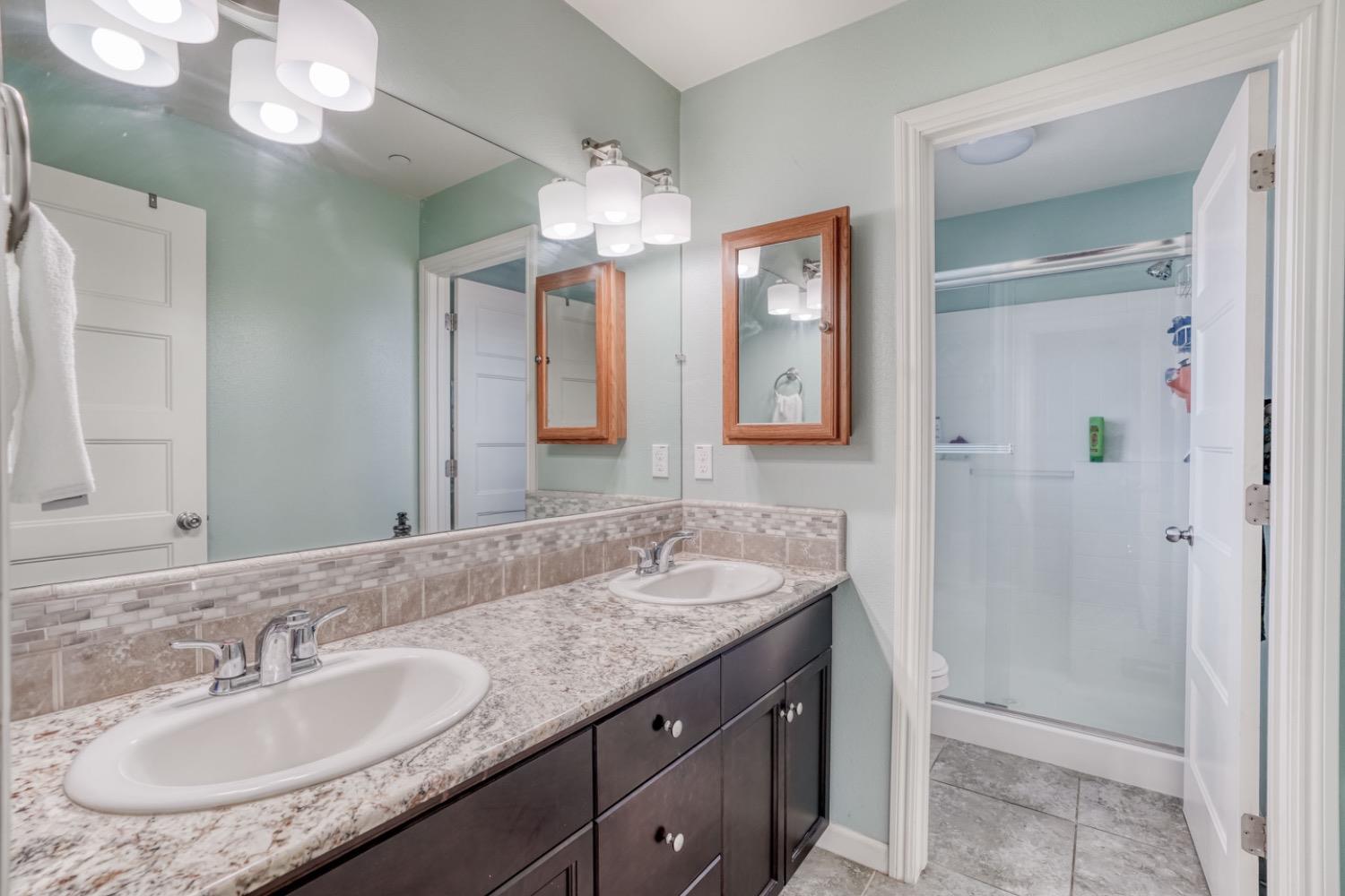 1503 North Reunion Way Clovis, CA 93619 - Photo 6 of 25 a bathroom with a granite countertop sink a light fixture and a mirror