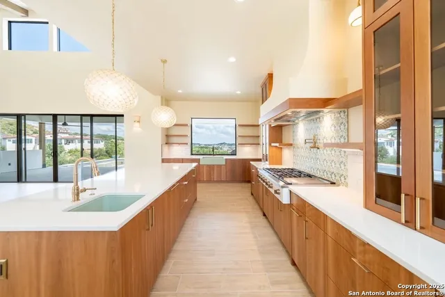 a large kitchen with kitchen island a large window a sink and stainless steel appliances