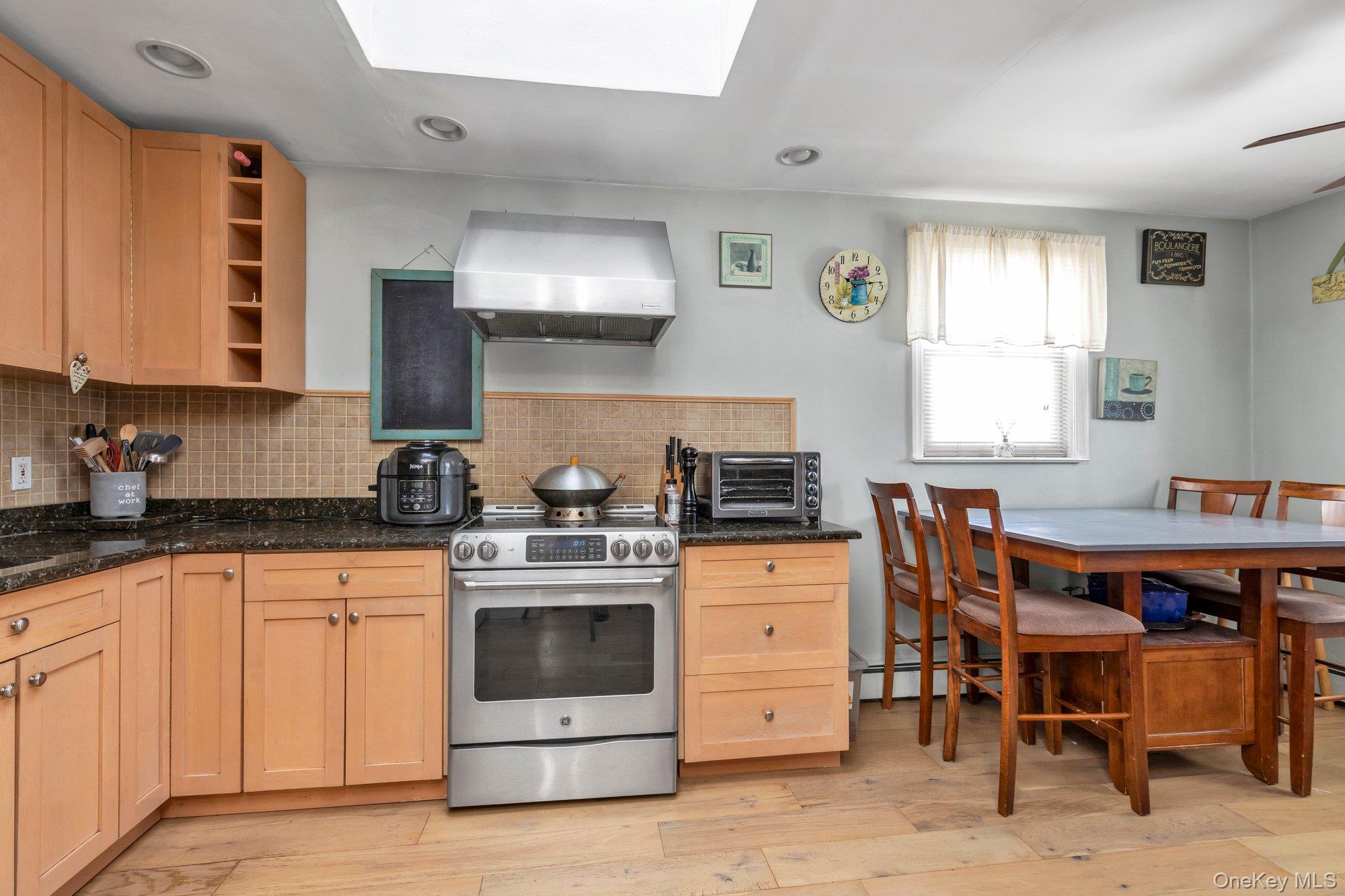412 Wellington Road East Meadow, NY 11554 - Photo 7 of 15 a kitchen with stainless steel appliances kitchen island granite countertop a table chairs sink and white cabinets