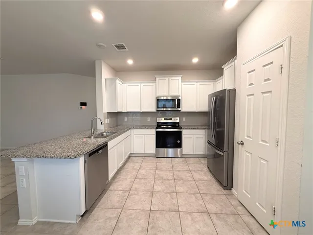 a large kitchen with stainless steel appliances granite countertop a refrigerator and a sink