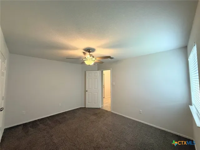 an empty room with a chandelier fan and windows