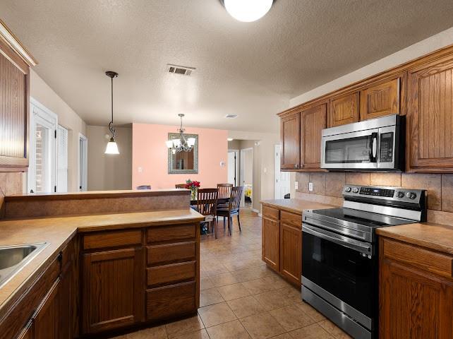 792 County Road 4213 Decatur, TX 76234 - Photo 11 of 32 Kitchen with stainless steel appliances, a textured ceiling, a peninsula, decorative light fixtures, and light countertops