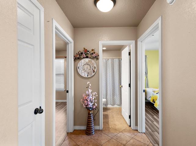 792 County Road 4213 Decatur, TX 76234 - Photo 25 of 32 Corridor featuring light tile patterned floors, a textured wall, and a textured ceiling