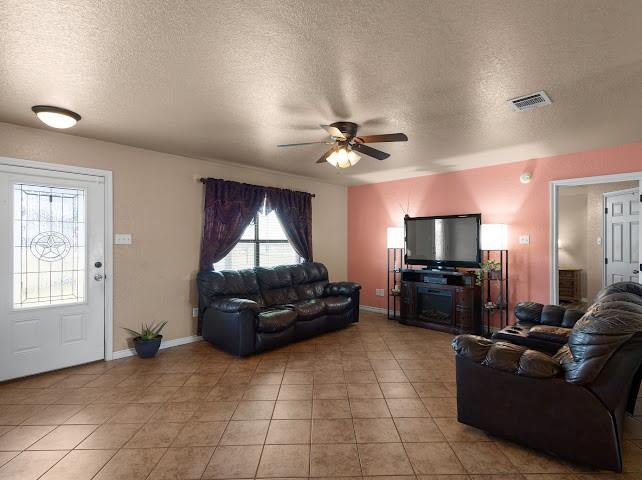 792 County Road 4213 Decatur, TX 76234 - Photo 5 of 32 Living area featuring a textured ceiling, ceiling fan, and light tile patterned floors