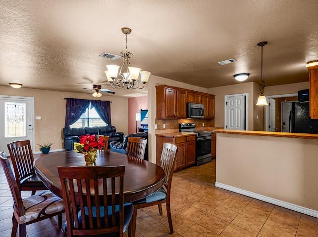 792 County Road 4213 Decatur, TX 76234 - Photo 9 of 32 Dining area with a textured ceiling, ceiling fan, a chandelier, and light tile patterned floors