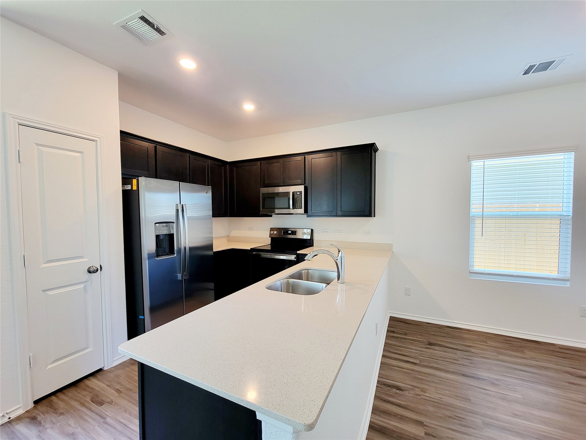 309 Bullhead Road Bastrop, TX 78602 - Photo 4 of 8 Kitchen featuring stainless steel appliances, light wood-type flooring, a peninsula, light stone countertops, and recessed lighting