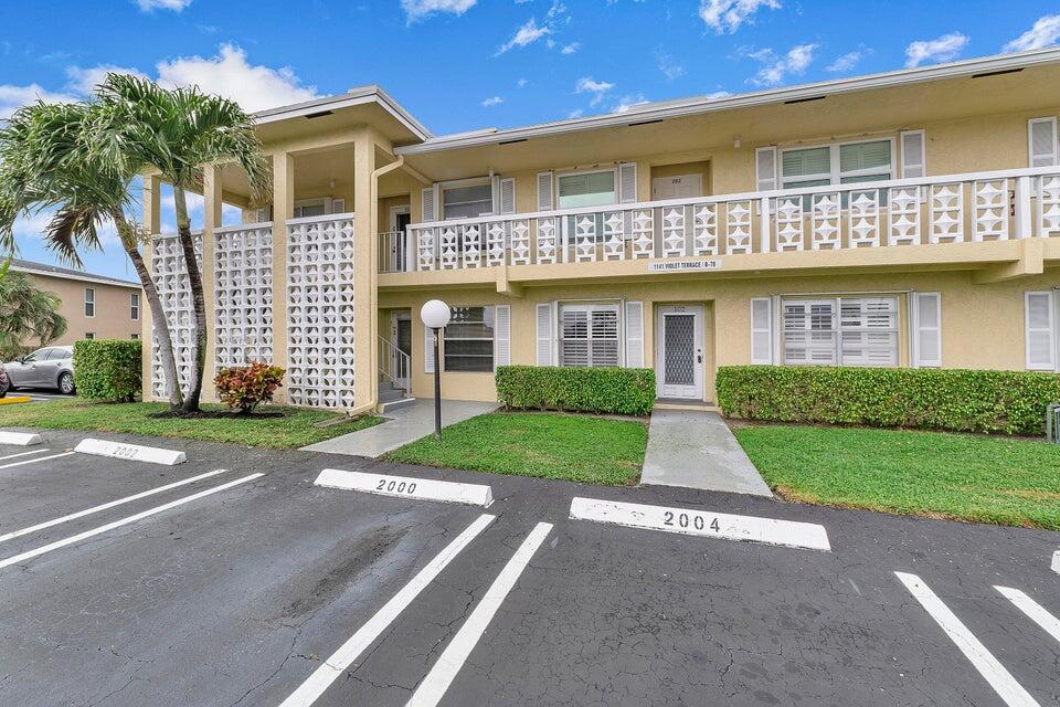 1141 Violet Terrace, Unit 101 Delray Beach, FL 33445 - Photo 15 of 29 a front view of a house with a yard and garage