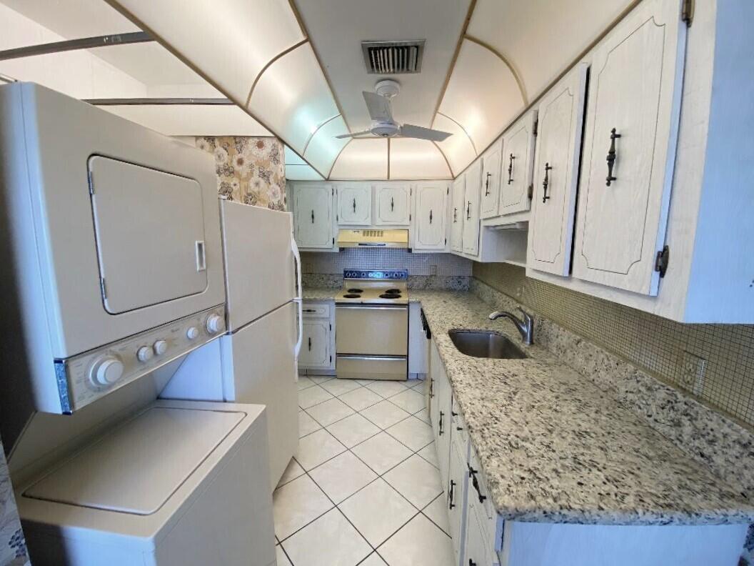 1141 Violet Terrace, Unit 101 Delray Beach, FL 33445 - Photo 29 of 29 a kitchen with stainless steel appliances granite countertop a sink a stove and cabinets