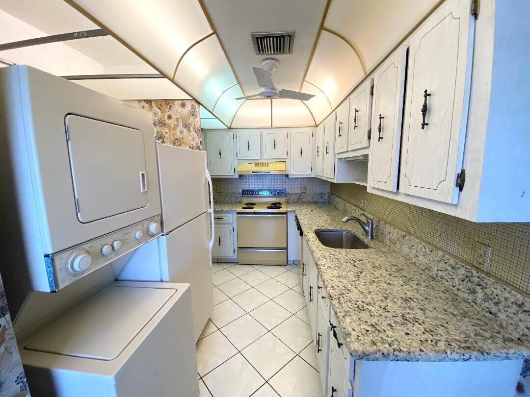 1141 Violet Terrace, Unit 101 Delray Beach, FL 33445 - Photo 4 of 29 a kitchen with stainless steel appliances granite countertop a sink a stove and cabinets