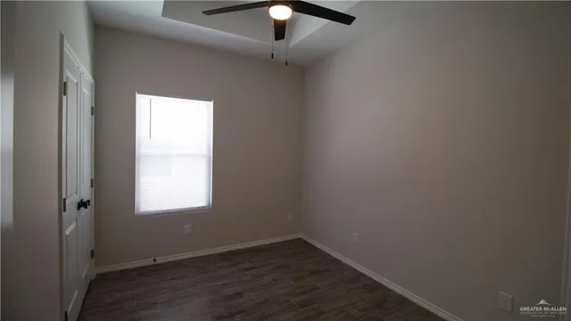 an empty room with wooden floor chandelier fan and windows