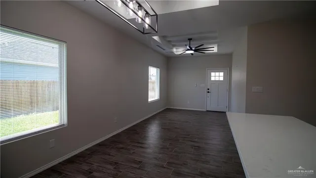 en empty room with windows and ceiling fan