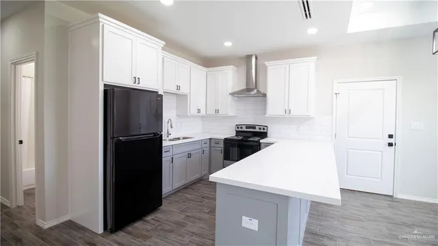 a kitchen with a refrigerator a stove top oven and white cabinets
