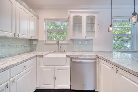 a kitchen with granite countertop white cabinets and a window